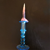 A dip candle burning in a holder