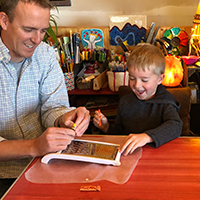 Father and son enjoying art and science with leaf pressing