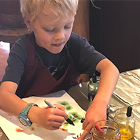 young boy writing his name on project